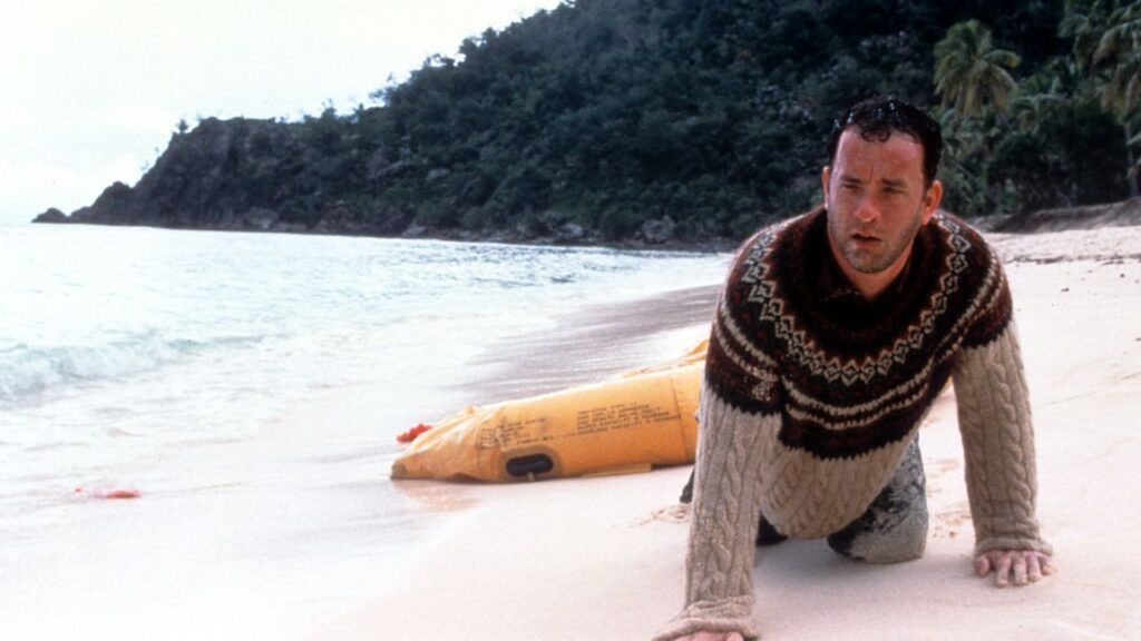 Tom Hanks with long beard sitting alone on an island in Cast Away.