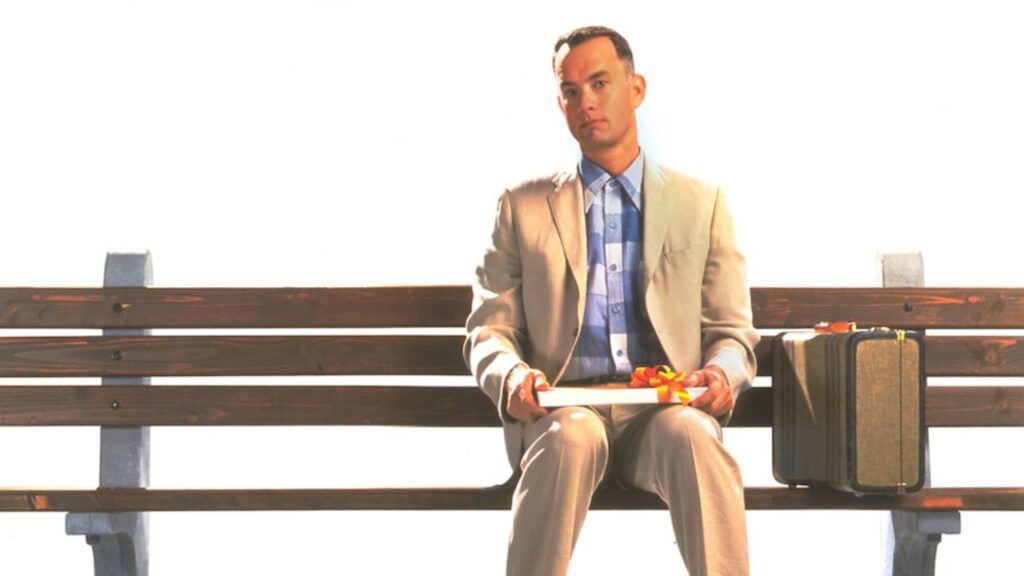Tom Hanks sitting on a bench as Forrest Gump in the movie poster.
